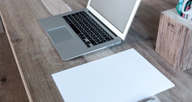 otvoren laptop i papir na stolu