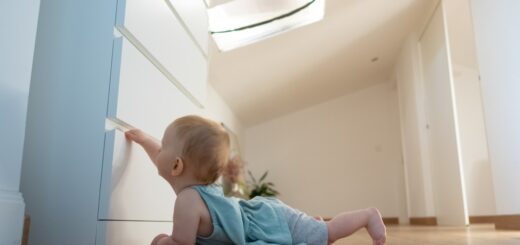 beba na stomaki+u napodu pokusava da otvori fioku od ormara