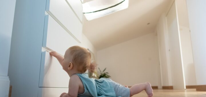 beba na stomaki+u napodu pokusava da otvori fioku od ormara