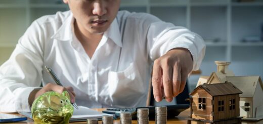 muskarac sa rasporedjenim metalnim novcicima i maketom kucice na stolu